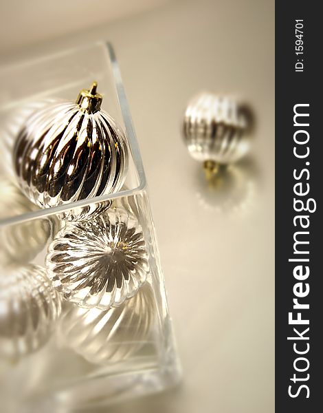 Silver christmas ornaments in glass bowl on reflective glass background. Silver christmas ornaments in glass bowl on reflective glass background