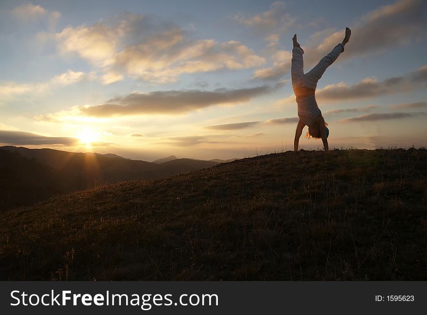 Acrobatic girl on grassland of sunrise. Acrobatic girl on grassland of sunrise