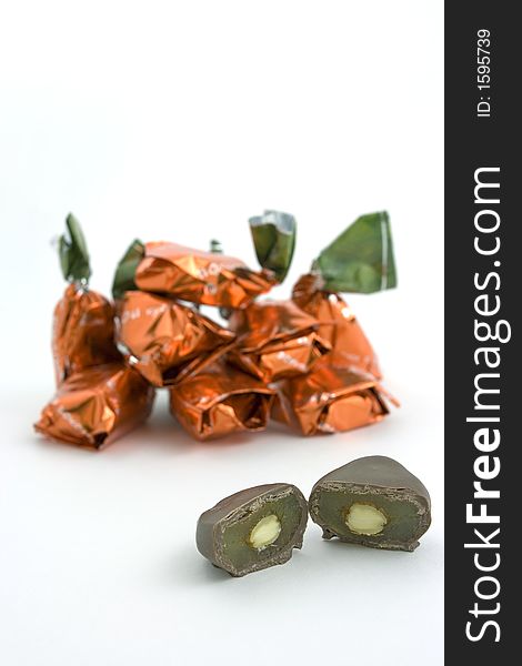 A sliced chocolate candy with almond and dried apricot filling and more wrapped candies on the back