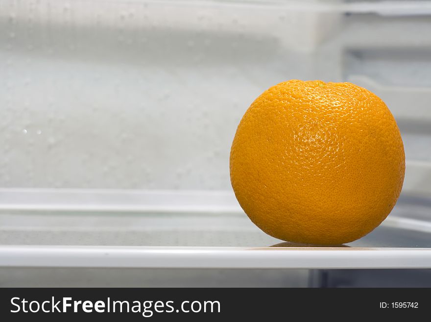 An orange inside fridge, sitting alone on the shelf. Copyspace provided.