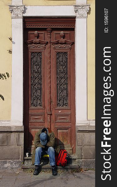 A man sits alone on an old house door