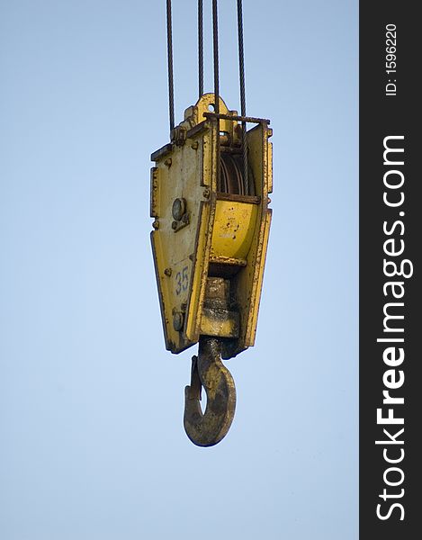 A yellow crane hook hanging from cables. A yellow crane hook hanging from cables