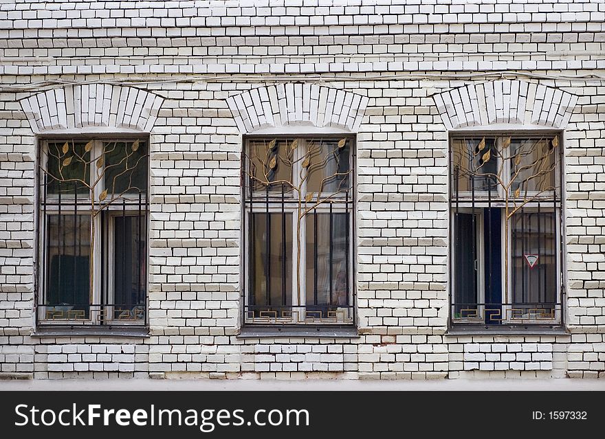 Three windows and a white brick wall