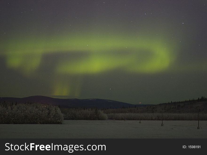 Swirl of northern lights over distant frozen forest. Swirl of northern lights over distant frozen forest