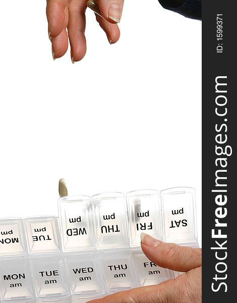 Female hands putting pills in a dispenser on white background isolated. Female hands putting pills in a dispenser on white background isolated