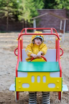 Small Girl In Yellow Rain Coat In Playground Car Royalty Free Stock Image