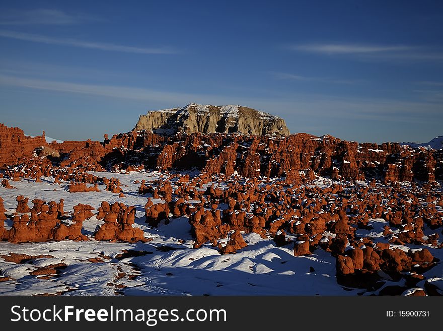 View of the red rock formations in Goblin Valley with blue sky�s and clouds and snow on the ground