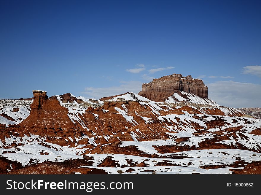 View of the red rock formations in Goblin Valley with blue skyï¿½s and clouds and snow on the ground