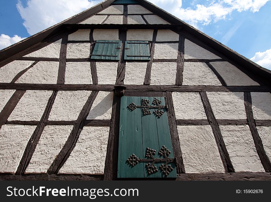 Architectural detail of half-timbered framework constructed home in Europe (Germany) complete with window shutters with ornate wrought iron hinges. Architectural detail of half-timbered framework constructed home in Europe (Germany) complete with window shutters with ornate wrought iron hinges