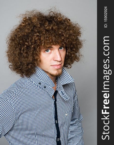 Young man with a curly hair on a gray background