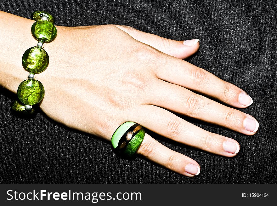 Green emerald bracelet and ring on woman hand, isolated on black background