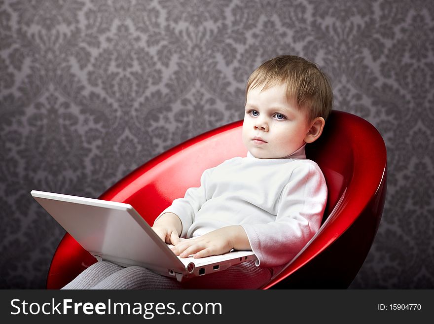 Image of boy sitting in a chair with a laptop