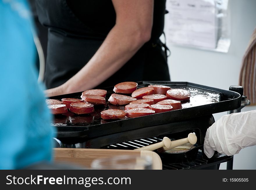 Slices of sausages cooking on a small grill. Slices of sausages cooking on a small grill