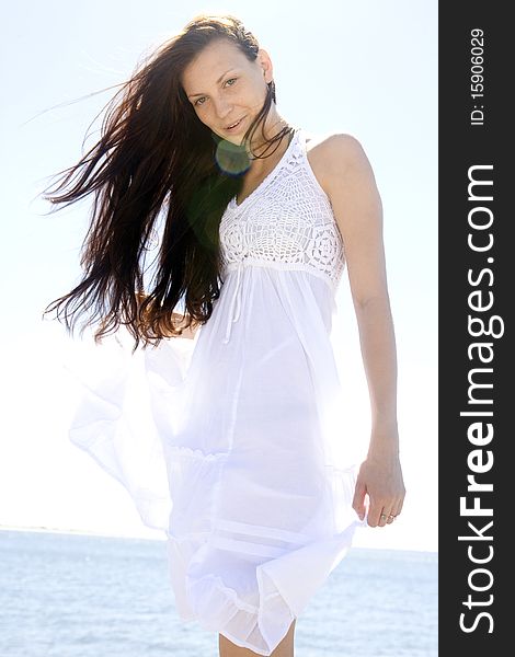 A beautiful young brunette woman dressed in white, seaside. A beautiful young brunette woman dressed in white, seaside
