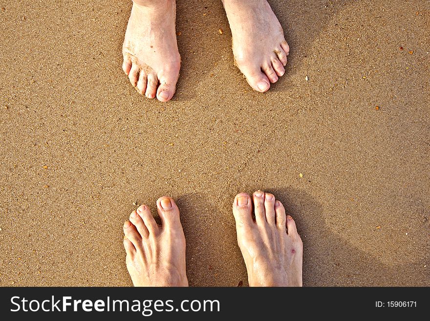 Feet of a couple at the sandy beach. Feet of a couple at the sandy beach