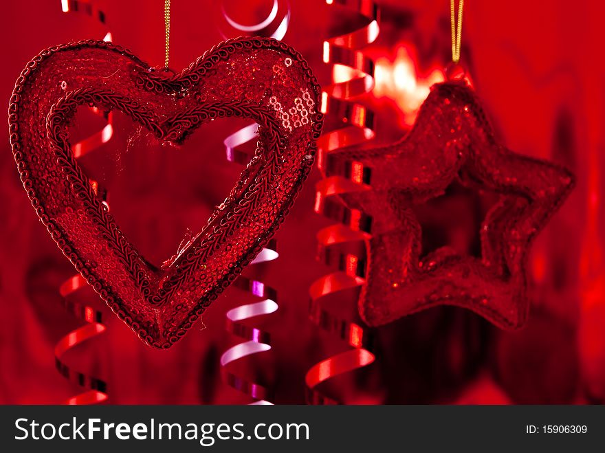 Red christmas baubles and ribbons on red background. Focus on heart. Red christmas baubles and ribbons on red background. Focus on heart