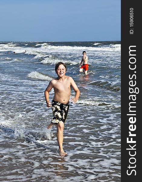 Boy running along the beautiful beach in the waves