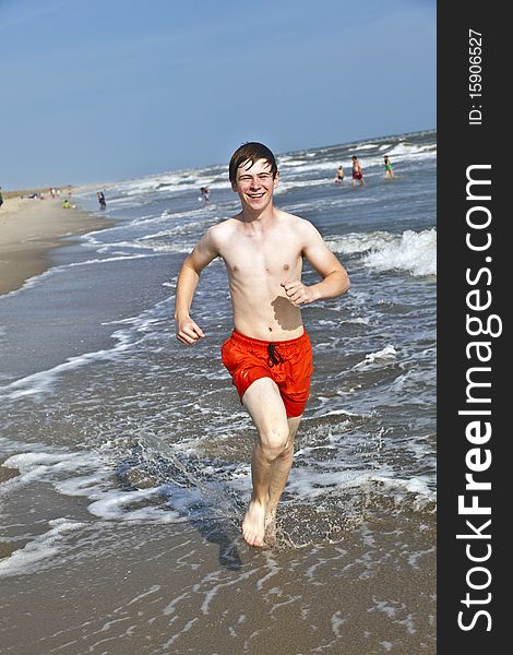 Boy running along the beautiful beach in the waves