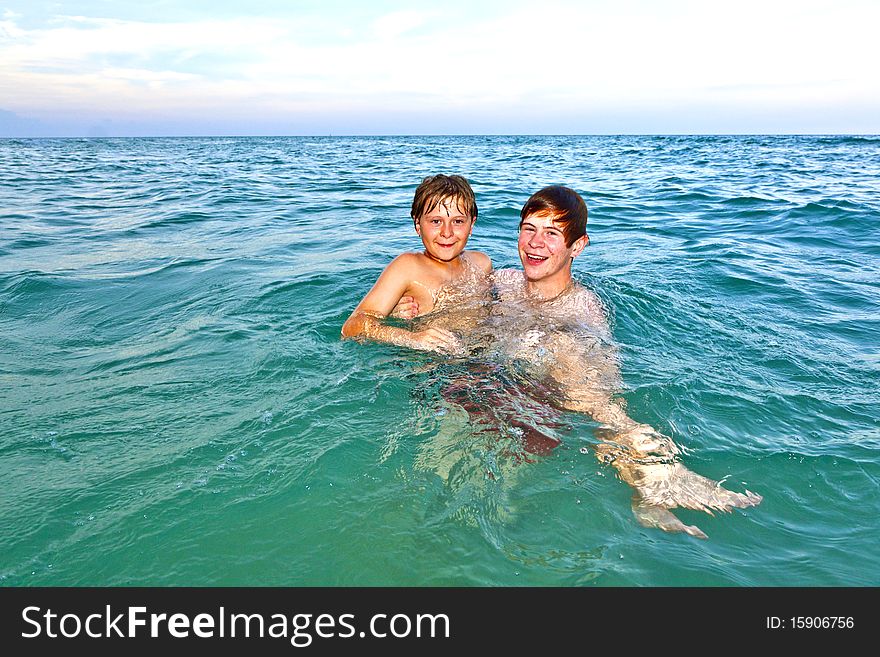 Brother holds his younger brother in his arms in the ocean. Brother holds his younger brother in his arms in the ocean