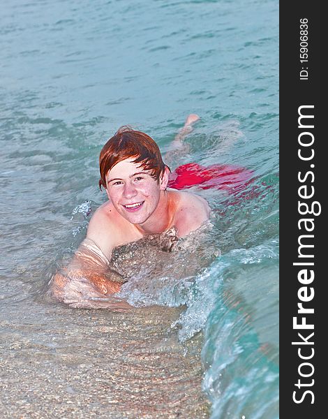 Young boy lying at the beach enjoys the surf of the ocean. Young boy lying at the beach enjoys the surf of the ocean