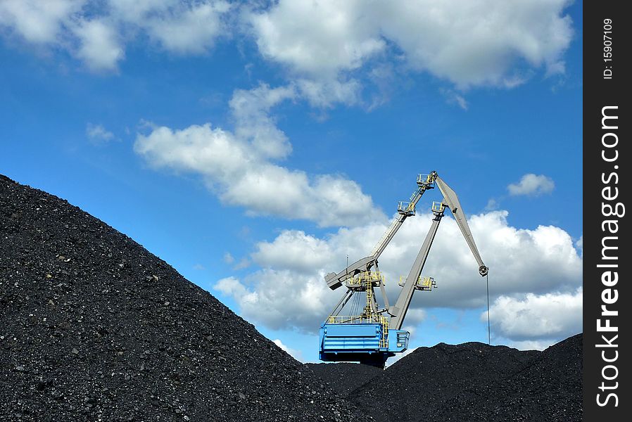 Crane loading coal against blue sky