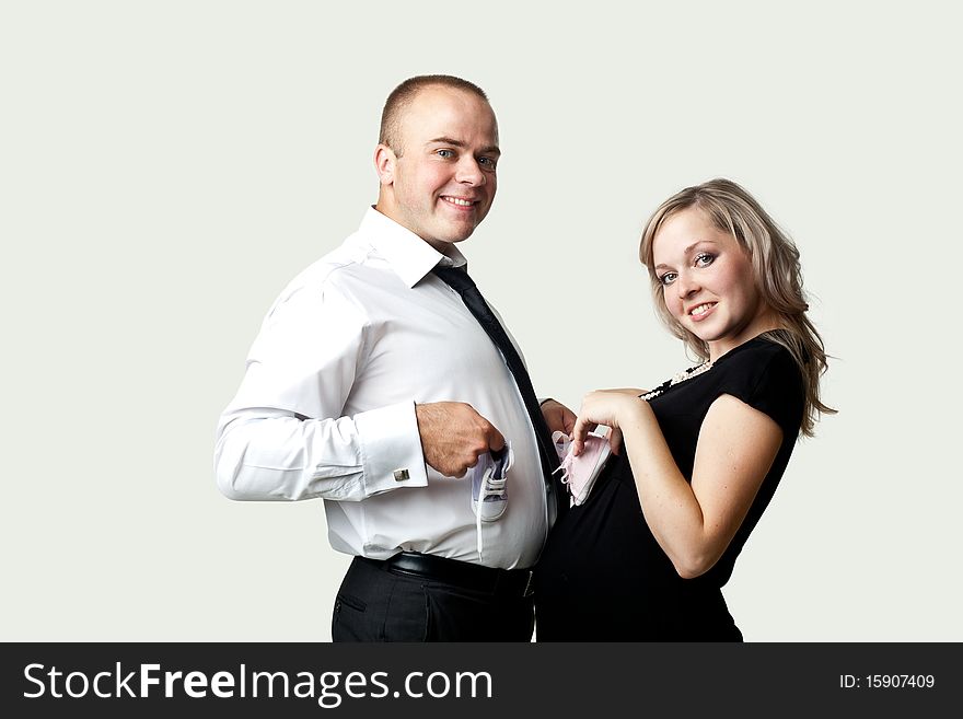 An image of a pregnant woman and her husband with little shoes. An image of a pregnant woman and her husband with little shoes