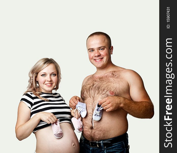 A young pregnant woman and her husband with little shoes. A young pregnant woman and her husband with little shoes