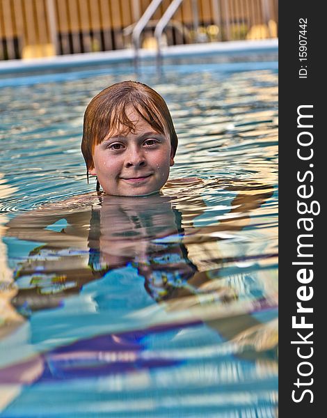 Boy enjoys swimming in an outdoor pool. Boy enjoys swimming in an outdoor pool