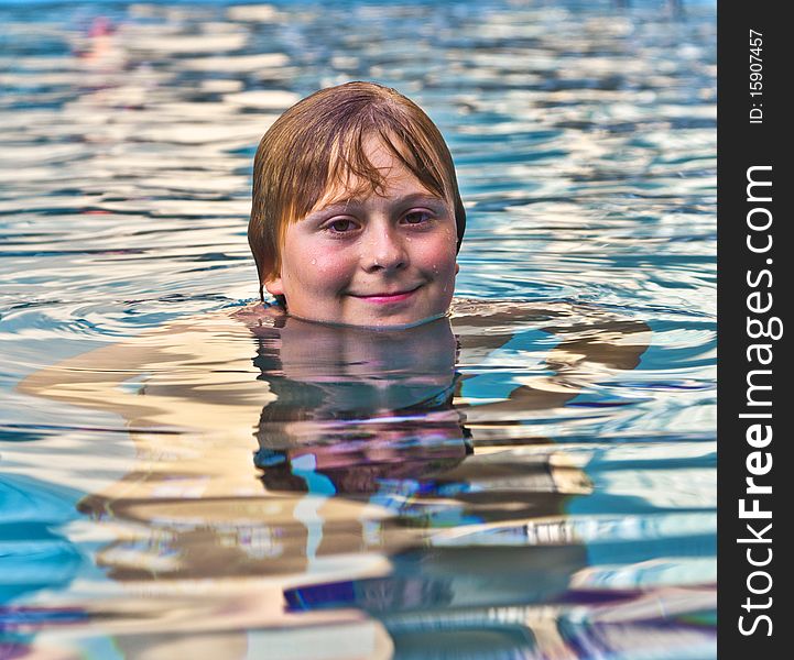 Boy enjoys swimming in an outdoor pool. Boy enjoys swimming in an outdoor pool