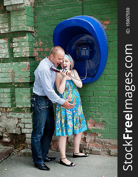 An image of a young couple at telephone in the street. An image of a young couple at telephone in the street