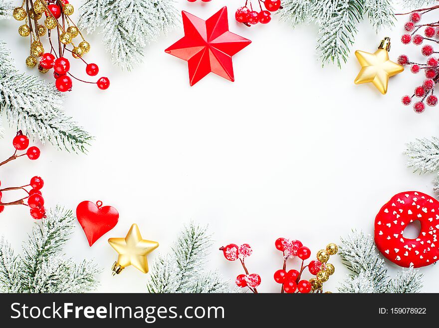 Christmas background. Xmas composition border with snowy fir branch, red holly berries, gold stars and baubles.