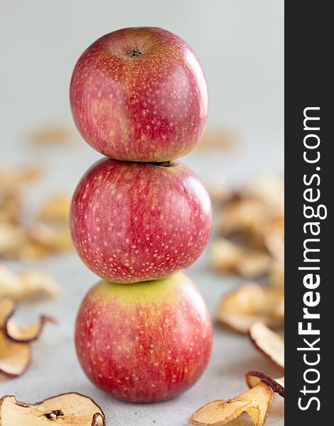 Stack of three fresh apples and Sun dried apple chips as a healthy snack, vertical composition