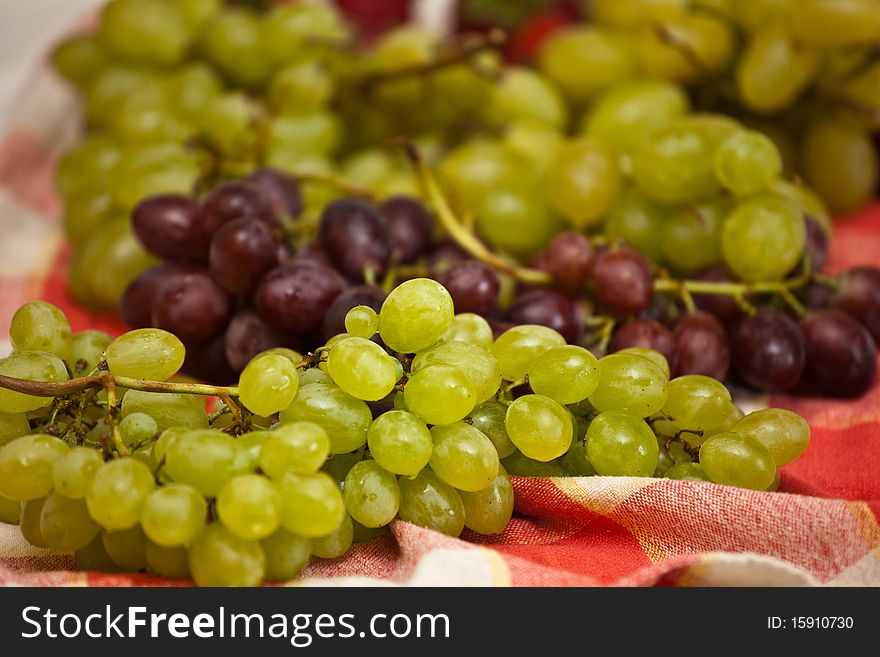 Ripe black and green grapes on red fabric