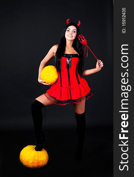 young brunette woman dressed as an imp with pumpkins