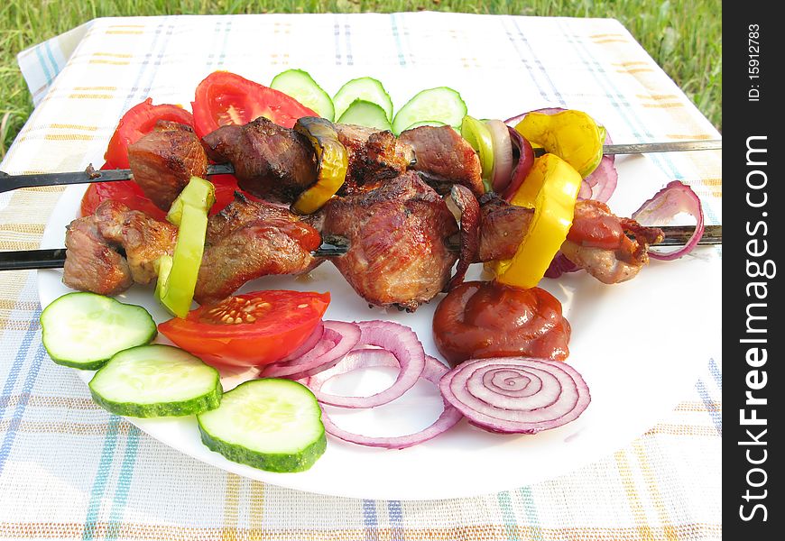 Grilled meat with pepper onion and cucumber roasting on plate barbecue outdoors. Grilled meat with pepper onion and cucumber roasting on plate barbecue outdoors