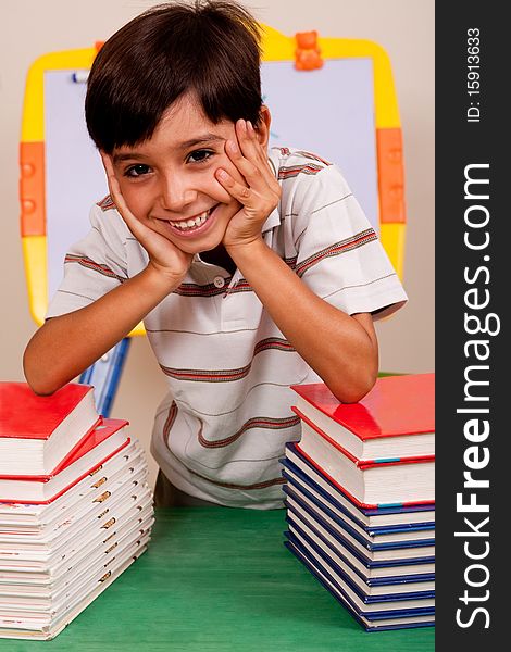 Young boy leaned over pile of books. Young boy leaned over pile of books