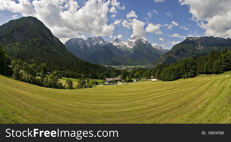 Wide angle panorama landscape taken in Lofer, Austria. A light green field in the foreground, mountains in the background and Lofer in between. Wide angle panorama landscape taken in Lofer, Austria. A light green field in the foreground, mountains in the background and Lofer in between