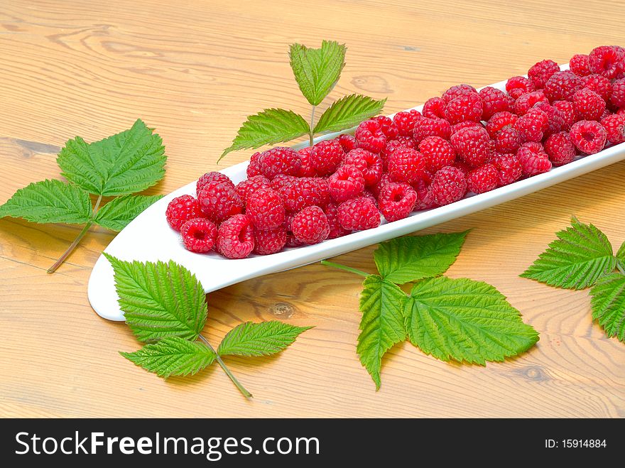 Raspberries with leaves on a wooden table. Raspberries with leaves on a wooden table.