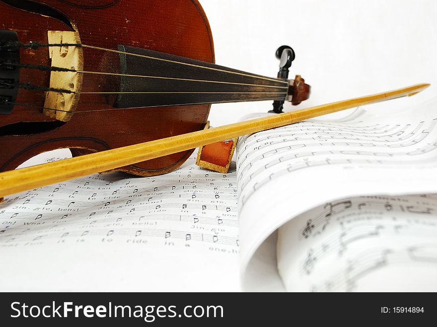 Violin with the bow and violin rosin on a white background and music books close up. Violin with the bow and violin rosin on a white background and music books close up