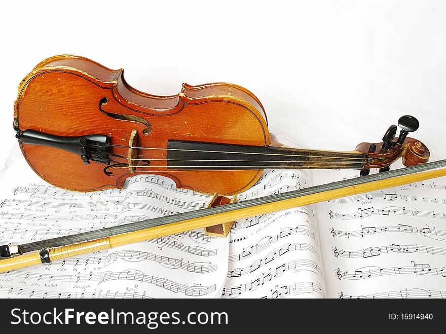 Violin with the bow and violin rosin on a white background and music books. Violin with the bow and violin rosin on a white background and music books
