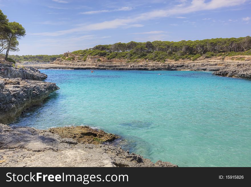 Wide view of sea bay with tarquoise water and rock shore in a sunny day. Mallorca, Spain. Wide view of sea bay with tarquoise water and rock shore in a sunny day. Mallorca, Spain.