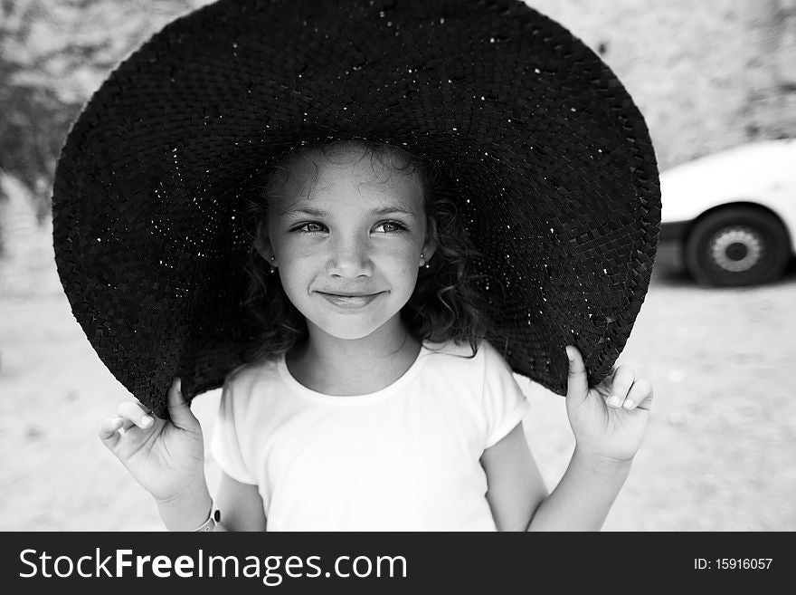 Outdoor portrait of a beautiful little girl in a wide hat