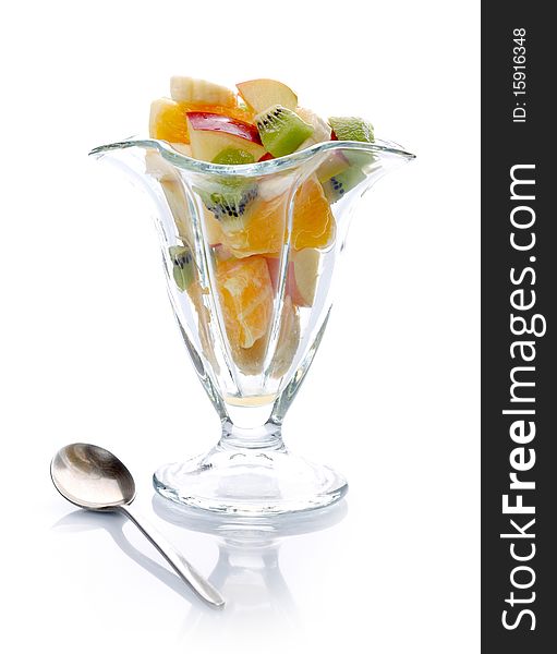 Fruit salad in glass bowl and spoon on white background