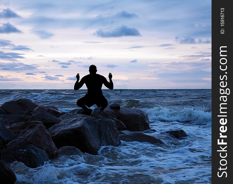 Man meditating on a stony sea shore