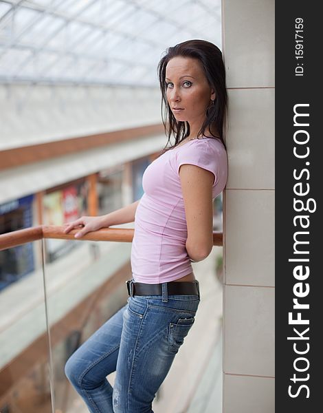 Portrait of a beautiful brunette on a balcony over a mall background