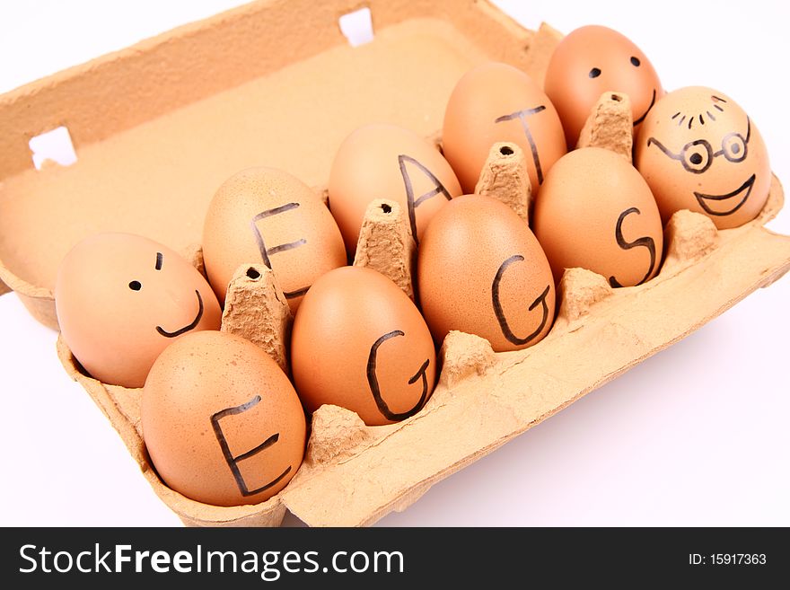 Eggs with an inscription EAT EGGS and some eggs with smiling faces in a carton