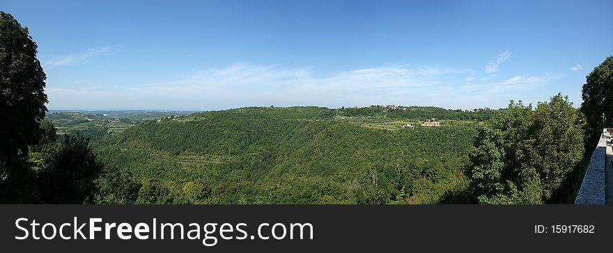 Panoramic landscape consisting of mountains, forests and sky with clouds