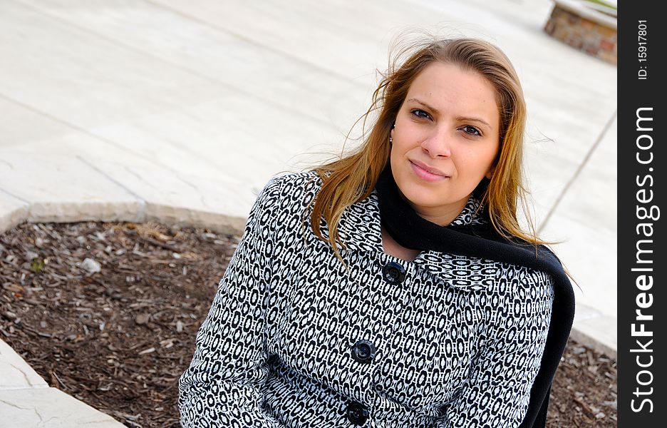 Attractive female is sitting on a concrete bench, in professional clothing. Attractive female is sitting on a concrete bench, in professional clothing.