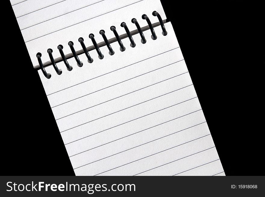 An open wire bound notebook with blank lined pages on a clean black background. An open wire bound notebook with blank lined pages on a clean black background