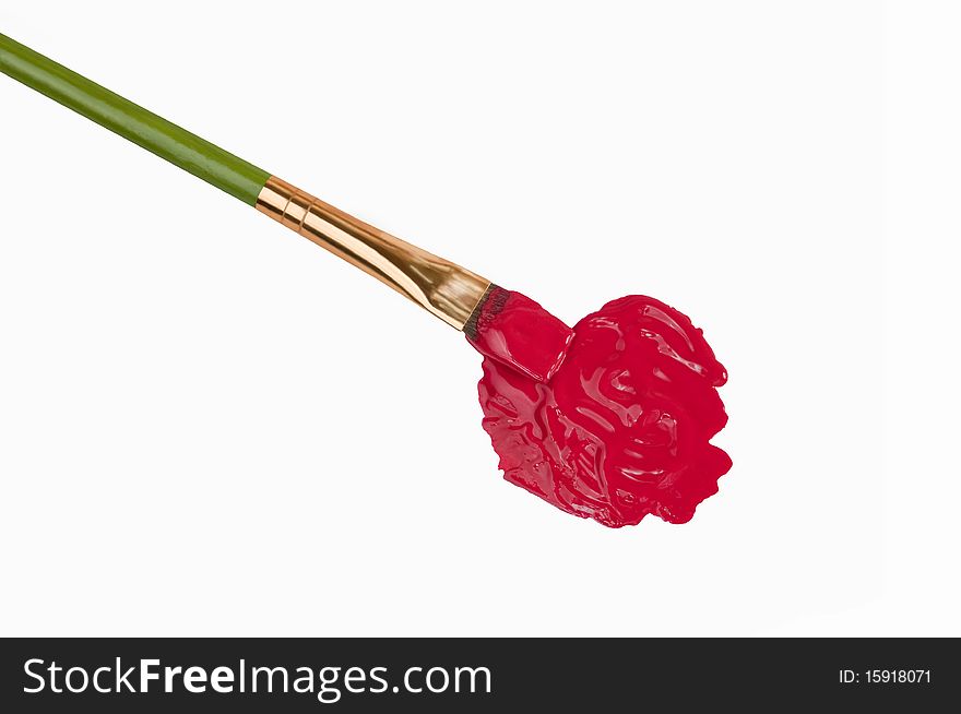 An artist paint brush rests diagonally in a blob of red paint on a clean white background. An artist paint brush rests diagonally in a blob of red paint on a clean white background